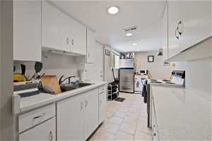 Kitchen with white range with electric cooktop, stainless steel fridge, white cabinetry, sink, and light tile floors