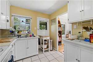 Kitchen featuring a wealth of natural light, white cabinets, light tile flooring, and range