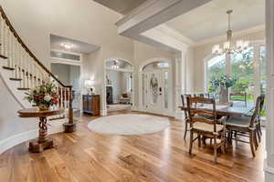 Entrance foyer featuring hardwood / wood-style floors, a notable chandelier, and crown molding