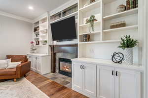 Living room featuring hardwood / wood-style floors, crown molding, and a tile fireplace