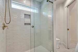 Bathroom featuring walk in shower, tile floors, and toilet