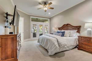 Bedroom with ceiling fan, access to exterior, light colored carpet, crown molding, and french doors