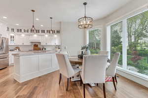 Dining room with light hardwood / wood-style floors and an inviting chandelier