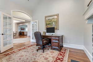 Office space with hardwood / wood-style floors, a towering ceiling, and french doors