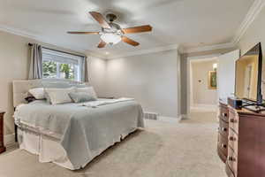 Bedroom with ornamental molding, light carpet, and ceiling fan