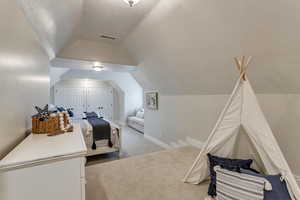 Bedroom with light colored carpet and vaulted ceiling