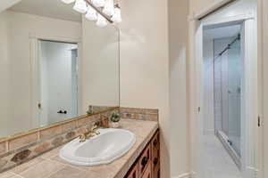 Bathroom featuring walk in shower, vanity with extensive cabinet space, and tile flooring