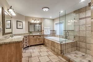 Bathroom with tile flooring, separate shower and tub, and dual vanity