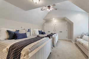 Bedroom featuring light colored carpet, ceiling fan, vaulted ceiling, and two closets