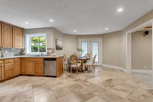 Kitchen with light tile flooring, french doors, backsplash, sink, and stainless steel dishwasher