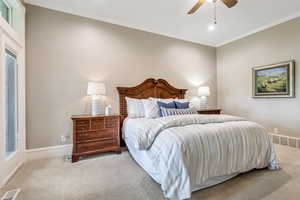 Carpeted bedroom with ornamental molding and ceiling fan