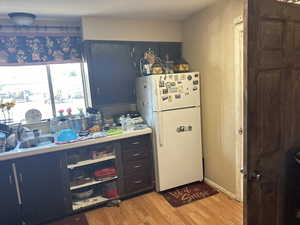 Kitchen featuring light wood-type flooring, a textured ceiling, sink, blue cabinets, and white refrigerator