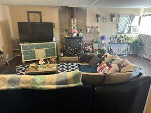 Other view of the Living room featuring cooling unit, hardwood / wood-style flooring, a fireplace, and a textured ceiling