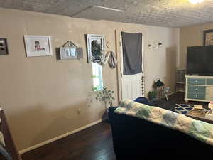 last view of the Living room featuring a textured ceiling and dark hardwood / wood-style floors