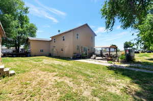 Back of house with a lawn and a patio