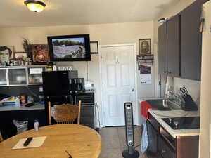 The old house front Kitchen features a black electric stovetop, sink, and dark tile patterned flooring