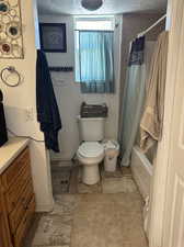 Full bathroom on the Building #2 downstairs featuring a textured ceiling, vanity, toilet, and shower / bath combination with curtain