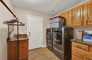 Laundry area featuring washer and dryer, a textured ceiling, light tile floors, sink, and cabinets