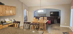 Kitchen with a center island, stainless steel fridge, light tile floors, and lofted ceiling