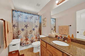 Full bathroom featuring shower / bathtub combination with curtain, tile floors, toilet, and vanity with extensive cabinet space