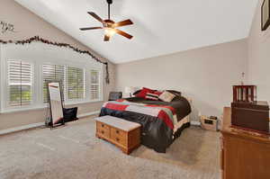 Carpeted bedroom with ceiling fan and vaulted ceiling