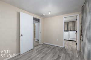 Spare room with washer and clothes dryer and light hardwood / wood-style flooring