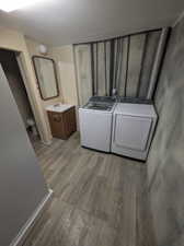 Laundry room featuring washing machine and clothes dryer, light hardwood / wood-style floors, and sink