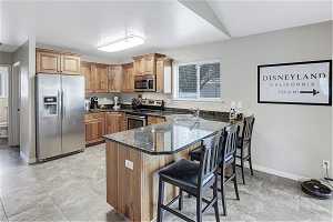 Kitchen with sink, a kitchen bar, stainless steel appliances, and light tile floors