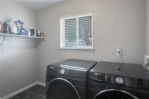 Washroom featuring dark tile flooring, washer hookup, and washer and clothes dryer