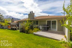 Rear view of house featuring a deck with mountain view and a lawn