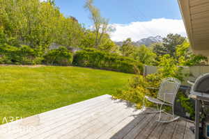 Wooden deck featuring a mountain view and a lawn