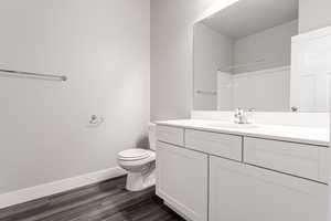 Bathroom featuring hardwood / wood-style flooring, vanity, toilet, and walk in shower