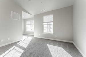 Carpeted spare room with lofted ceiling