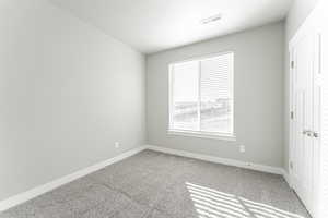 Empty room featuring a textured ceiling and carpet floors