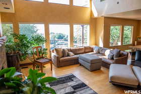 Living room featuring hardwood / wood-style flooring, a wealth of natural light, and a towering ceiling