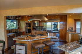 Kitchen with appliances with stainless steel finishes, wall chimney range hood, and a kitchen bar