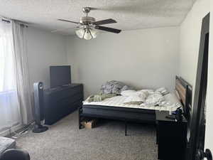 Carpeted bedroom with ceiling fan and a textured ceiling