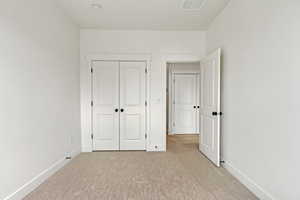 Unfurnished bedroom with light carpet and a closet