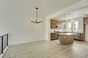 Kitchen with a chandelier, light hardwood / wood-style flooring, stainless steel appliances, hanging light fixtures, and a center island