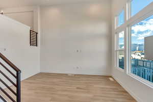 Empty room featuring light wood-type flooring and a towering ceiling