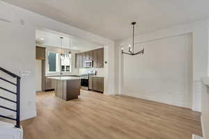 Kitchen featuring a center island, an inviting chandelier, light hardwood / wood-style flooring, decorative light fixtures, and stainless steel appliances