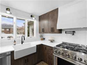 Kitchen featuring appliances with stainless steel finishes, premium range hood, backsplash, wood-style flooring, and sink