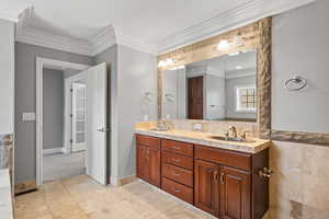 Bathroom featuring tile floors, dual sinks, ornamental molding, and large vanity