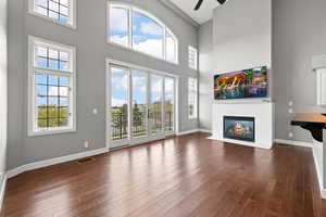 Unfurnished living room featuring a high ceiling, french doors, dark hardwood / wood-style floors, and ceiling fan