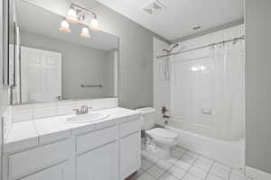 Full bathroom featuring vanity with extensive cabinet space, shower / bath combination with curtain, tile flooring, and toilet