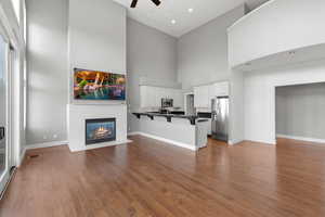 Unfurnished living room featuring a high ceiling, wood-type flooring, and ceiling fan