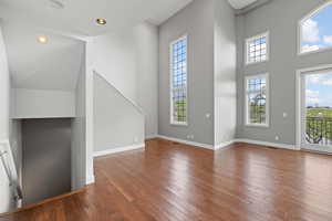 Unfurnished living room with a high ceiling, plenty of natural light, and hardwood / wood-style floors