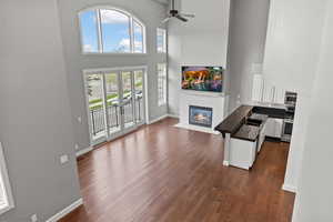 Living room featuring dark wood-type flooring, a towering ceiling, sink, and ceiling fan