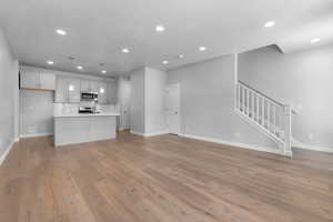 Kitchen with hanging light fixtures, tasteful backsplash, a kitchen island, light hardwood / wood-style flooring, and stainless steel appliances