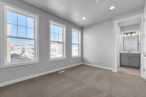 Unfurnished bedroom with light carpet, sink, and ensuite bath